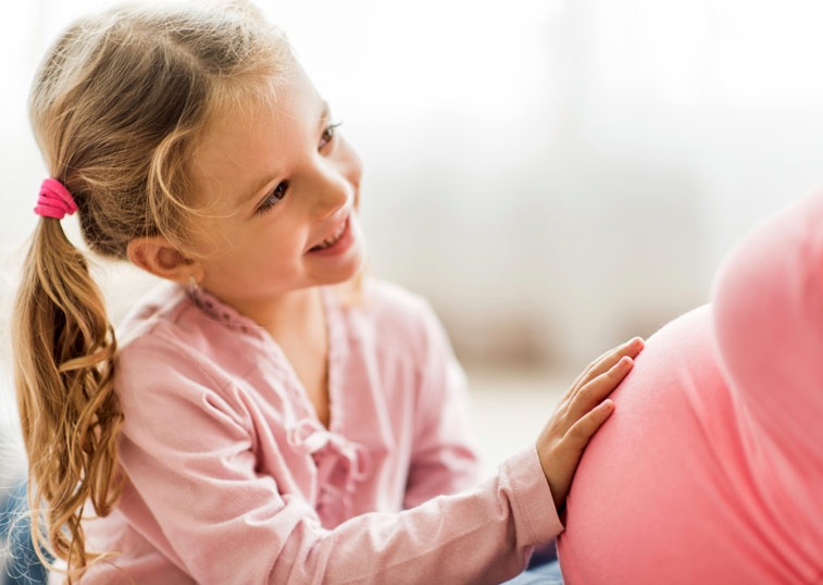 Little girl touching mom's pregnant belly