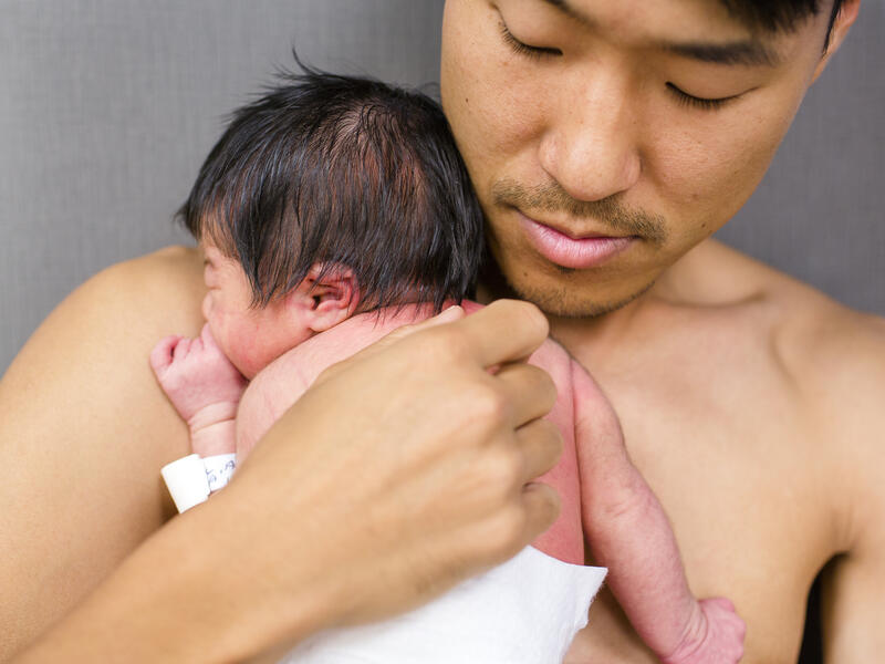 A new father rests peacefully skin-to-skin with his newborn baby girl.