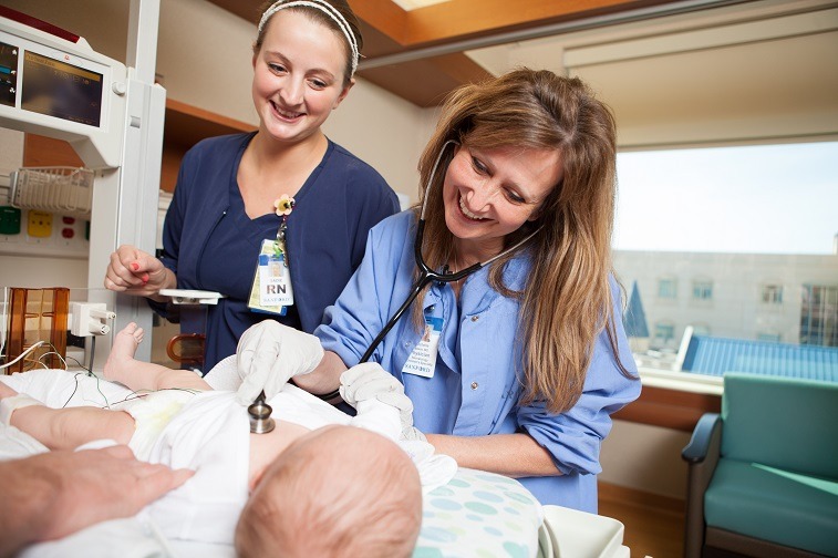 nurses looking at newborn baby