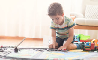Little boy, 3-4 years, playing alone with train and toys at home