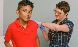 A boy receives a vaccination from a female health care worker. Boys and girls should receive the HPV immunization, ideally at age 11 or 12