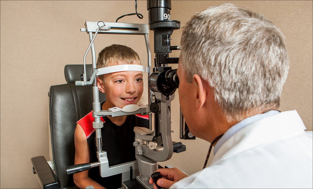An eye doctor looks for vision problems at a child's eye exam.