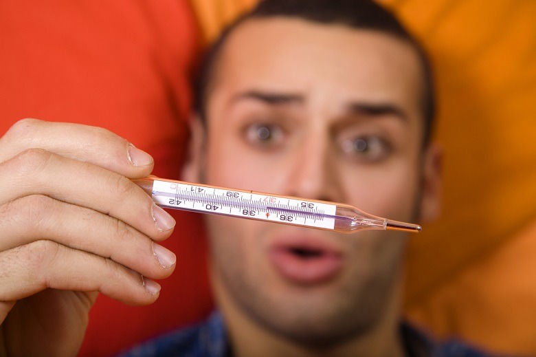 man with flu taking his temperature