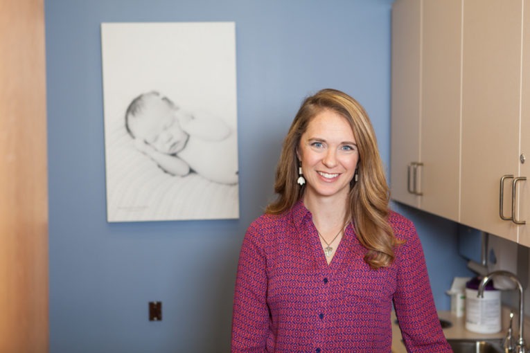 Midwife Erin VandeLune standing in front of a blue wall