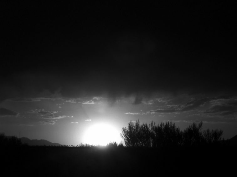 black and white image of a sunrise with clouds overhead
