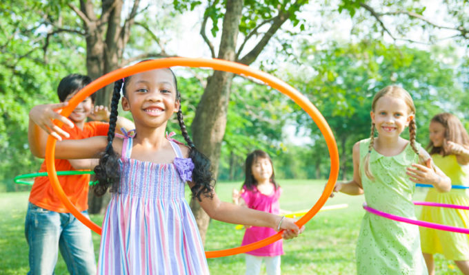 Young girls and boys playing with hula hoops in the park