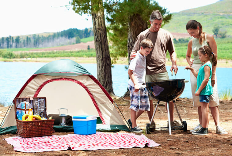 Family camping and grilling out by lake