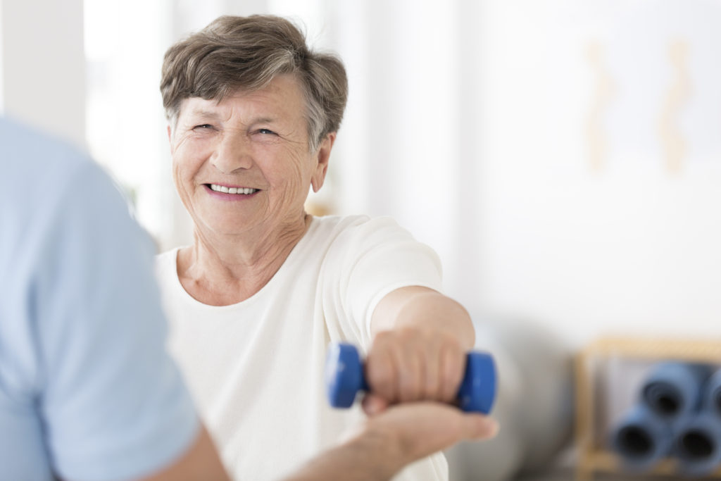 Senior women exercising arms with small weight in hand