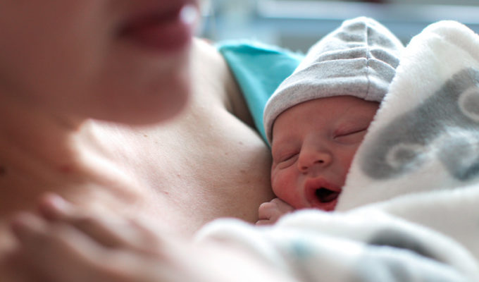 A newborn baby boy breastfeeding for the first time in hospital.