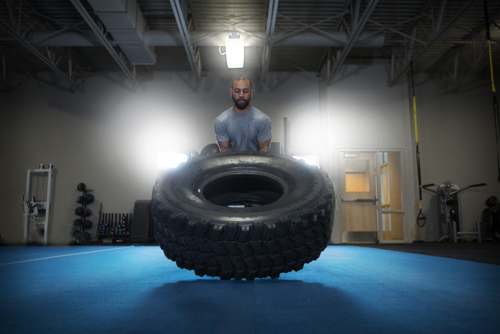 Male lifting a tractor tire at the wellness center