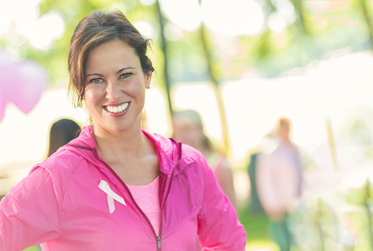 woman wearing pink with breast cancer ribbon smiling