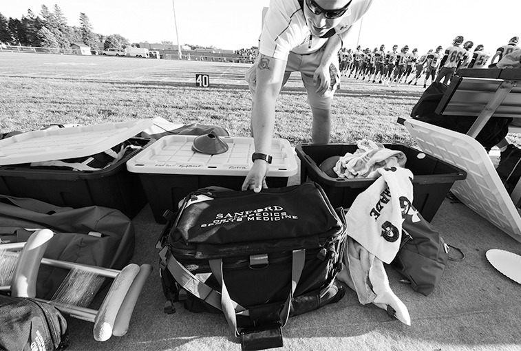 Hawley reaches for supplies in his Sanford Orthopedic and Sports Medicine bag on the sidelines before the Sept. 7 game. With the well-being of the players in mind, Hawley is equipped with items including ice, bandages, tape, crutches and more.