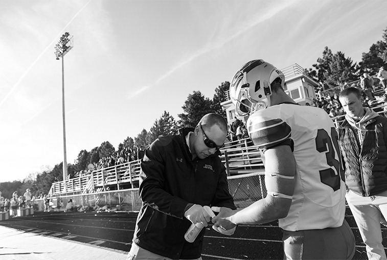 Hawley sprays disinfectant on a player's hand wound before game time on Sept. 28, 2018. 