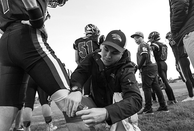 Hawley prepares a player by taping up his knee on the sidelines before the Sept. 28 game.