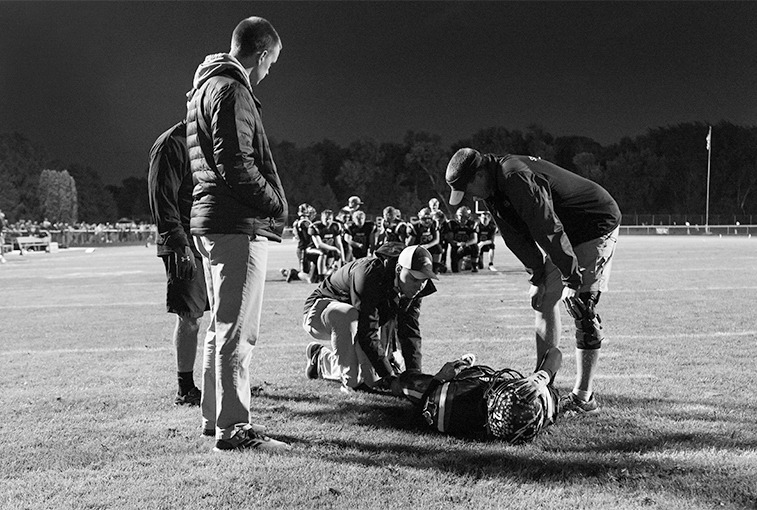 Hawley assesses a knee injury of C-Hawk's Cody Soderquist on the field after a violent tackle during the Sept. 28 game. 