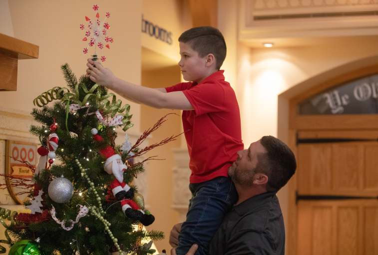 Rod Hunter, whose team decorates for Christmas at the Castle in Sioux Falls, S.D., lifts son Layton.