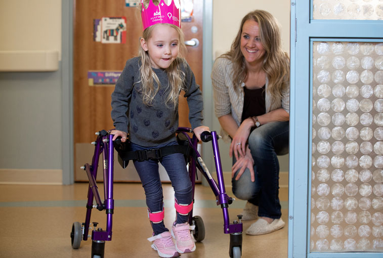 Avery Hill practices using her walker with her mom, Mindy Hill.