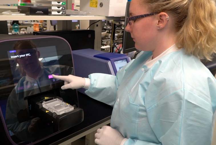 Alexandra Mohror, a clinical genetics laboratory technician, loads that tray into a machine that will mix the chemicals with the DNA. That's done by a robot squeezing both sides into a gray area in the center of the tray that contains small wells where certain reactions take place.