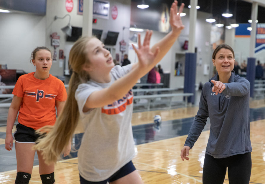 Two girls play volleyball while Courtney Thompson coaches them