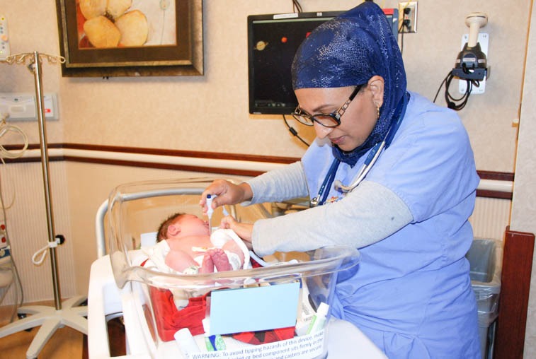 Eskedar Yimer, an RN at Sanford Health's Birth Place, checks baby Thomas' temperature. 
