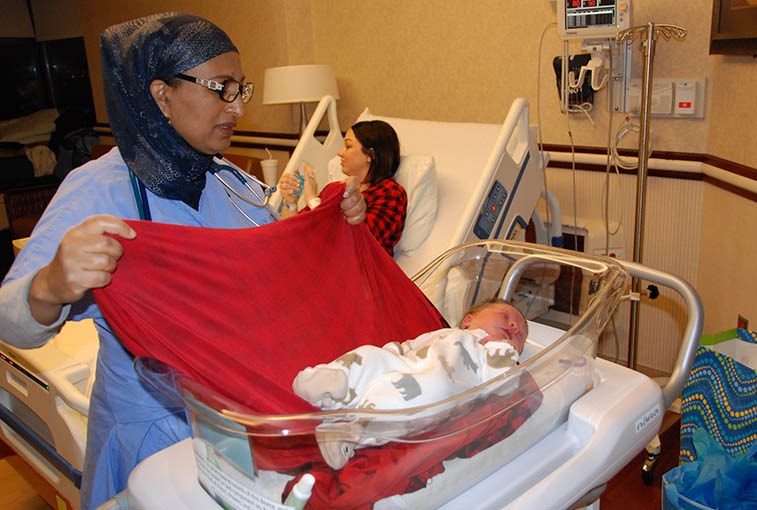 Eskedar Yimer, RN, checks on baby Thomas while his mom, Danielle Svartoien, talks with guests in her Sanford Health Birth Place room.