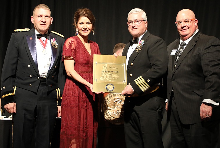 Sanford Health receives the South Dakota Employer Support for the Guard and Reserve Pro Patria Award during the South Dakota National Guard Dining-Out in Pierre, S.D., Feb. 7, 2019. Pictured left to right: Maj. Gen. Tim Reisch, SDNG adjutant general; Gov. Kristi Noem; retired U.S. Navy Capt. Paul Weckman, Sanford Health director of diversity, inclusion, veterans and military services; and Jim White, ESGR-SD chair. (U.S. Army National Guard (Photo by Staff Sgt. Heather Trobee)