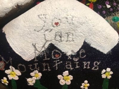 Black and white painted rock that says 'You Can Move Mountains'