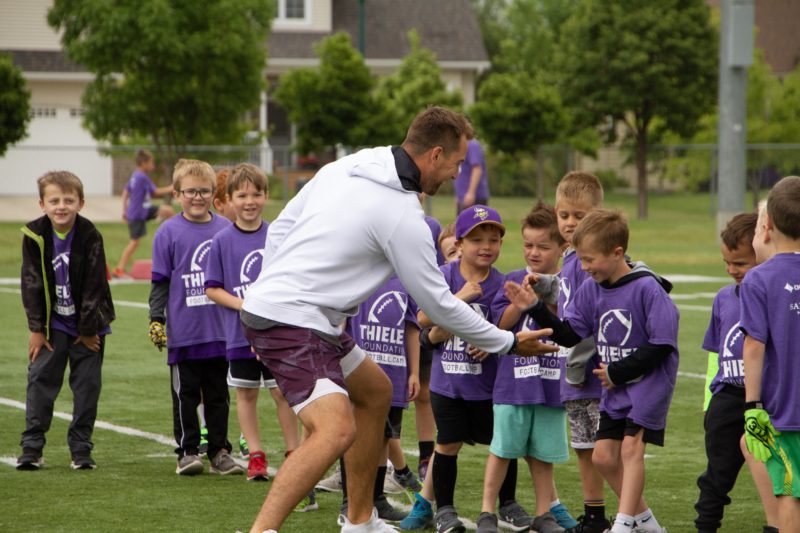 Adam Theilen, an All-Pro wide receiver for the Minnesota Vikings, high-fives kids at football camp June 20 in Fargo, North Dakota.