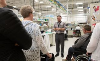 Dr. Peter Vitiello speaks with a group of people with walkers and wheelchairs in a research lab.