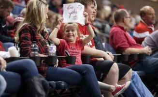 Girl in red shirt holds a handmade "Go Yotes" sign. The USD Coyotes will play volleyball at the Sanford Pentagon for the first time in October.
