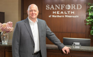 Bryan Nermoe stands at the front desk of Sanford Health of Northern Minnesota.
