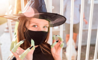 Happy girl with artificial nails and witch hat followed by protective mask.