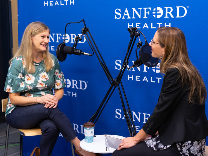 Larissa Risty and Jacqueline Palfy having a conversation in front of podcast microphones