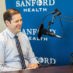 Steven Powell smiling in front of podcast microphone