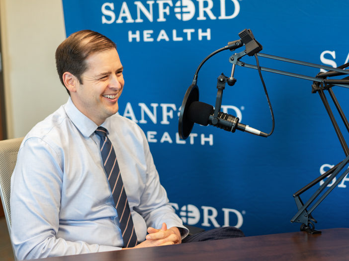Steven Powell smiling in front of podcast microphone