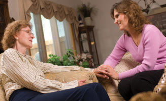 Aging in place: Mother and daughter holding hands in living room