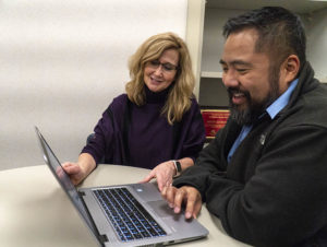 Dr. Michelle Baack and Dr. Randy Raustino sit at a table with a laptop open as they look over heart research information.