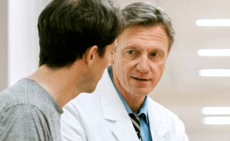 doctor in white coat talks to male visitor