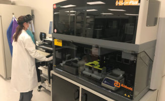 Lab technician in full protective gear processes coronavirus tests