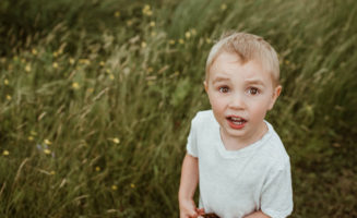 Young boy outside looks up with questioning look.