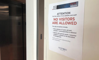 White metal door with sign that says ATTENTION: NO VISITORS ARE ALLOWED