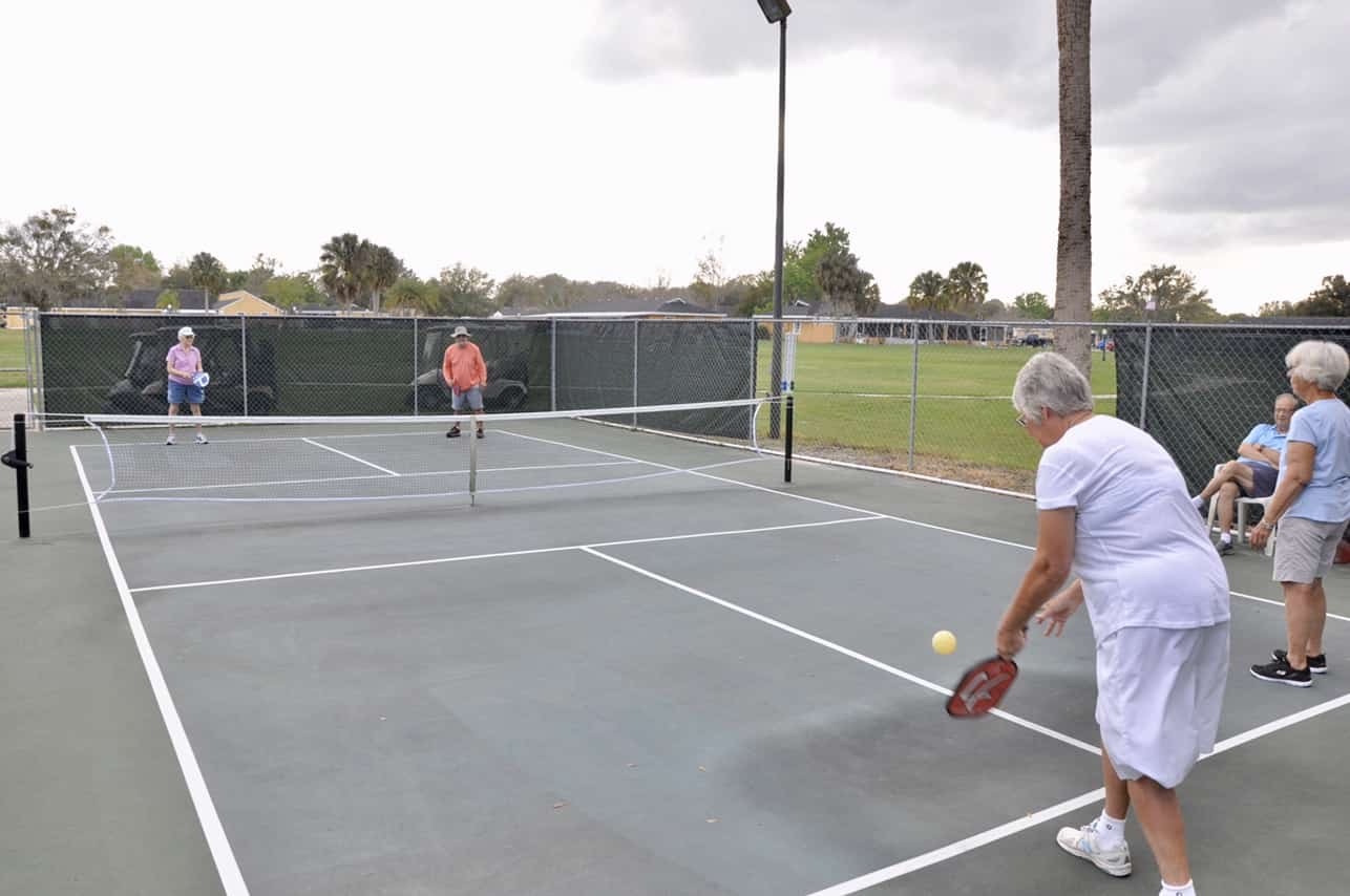 Older adults play pickleball on an outdoor tennis court at Good Samaritan Society-Kissimmee Village.