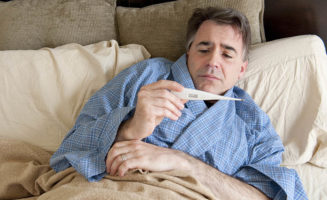 A man holds a thermometer in a photo representing a home monitoring program