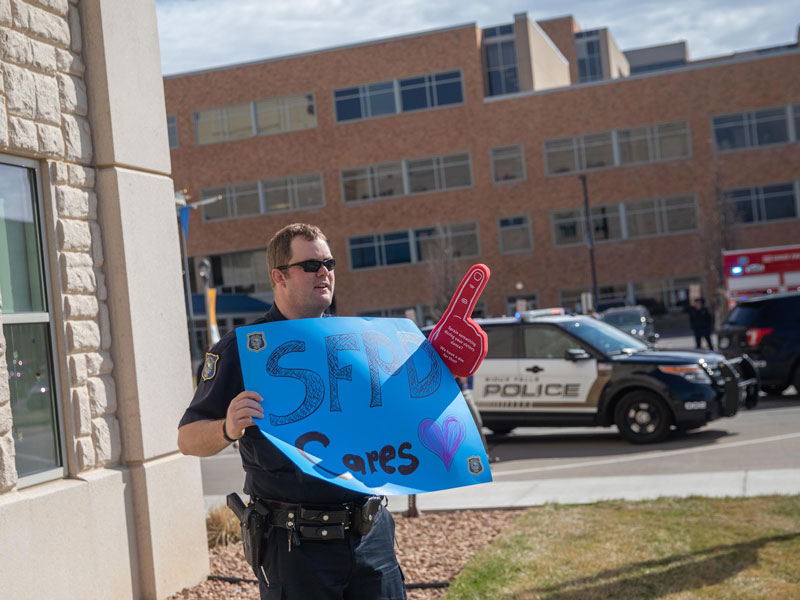 A police officer carries a poster to the windows of patients on the first floor. (Photo by Jay Pickthorn, Sanford Health)