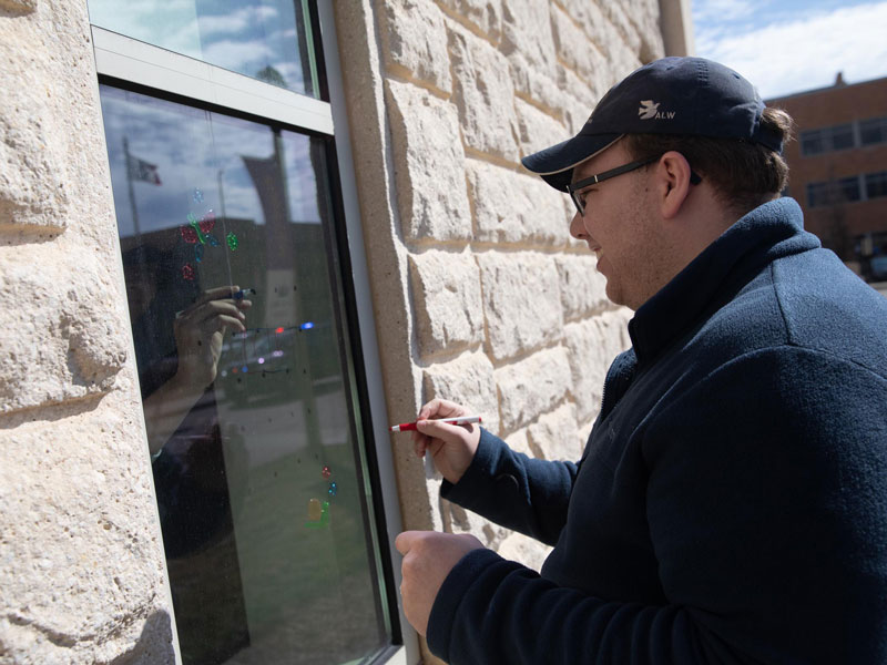 A staff member plays a game with a children's hospital patient on their window. (Photo by Jay Pickthorn, Sanford Health)