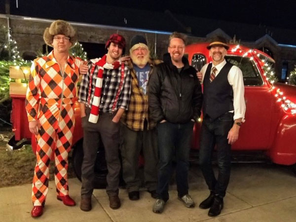 Five men, members of the band Meat Rabbits, pose in suits and winter gear in front of a red truck.