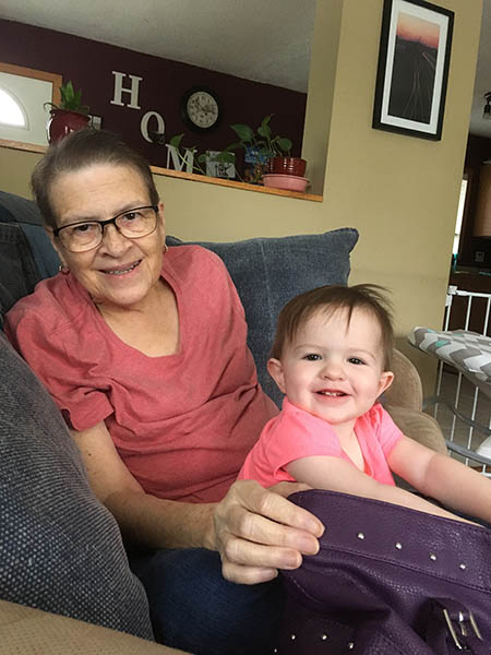 Brenda Russ smiles and holds a baby grandchild on her lap