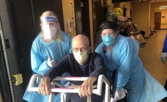 COVID-19 patient in a wheelchair leaves hospital with nurses in full PPE