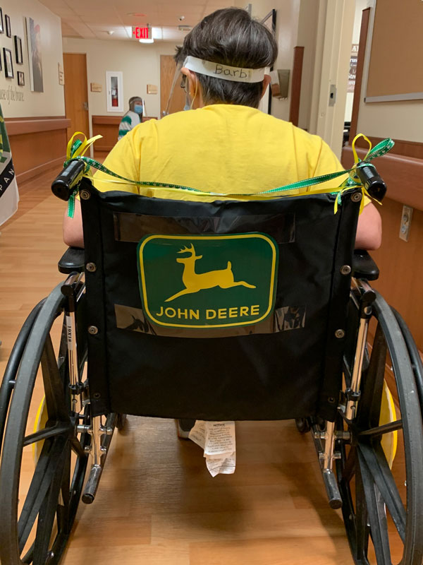 A nursing home resident models a wheelchair decorated with a John Deere sign