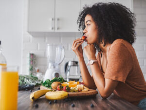 Young woman eating a healthy snack with fruit at home.